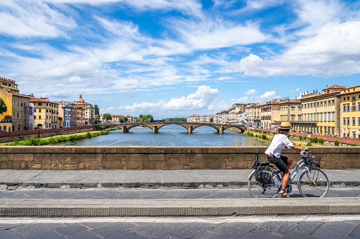 Florence, Italy - August 11, 2017: A person in a Bicycle riding over a bridge in Florence