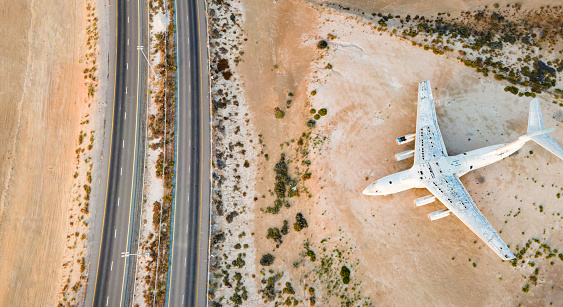 Deserted airplane by the highway in the desert of Umm Al Quwain emirate of the United Arab Emirates aerial view at sunrise