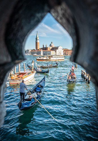 Venice, Italy – August 13, 2017:  Gondola full of people with San Giorgio Maggiore island on the background
