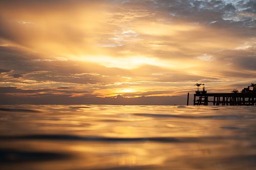 shoot from water surface in the sunset with pier on horizon