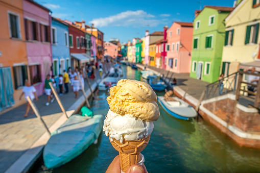 Hands holding  two flavours ice cream in waffle cone in Burano, Italy