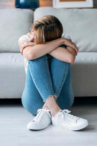 istock Depresive young woman thinking about her problems while sitting on the floor in the living room at home. 1262957095