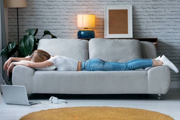 istock Exhausted young woman lying down on sofa at home. 1262957109