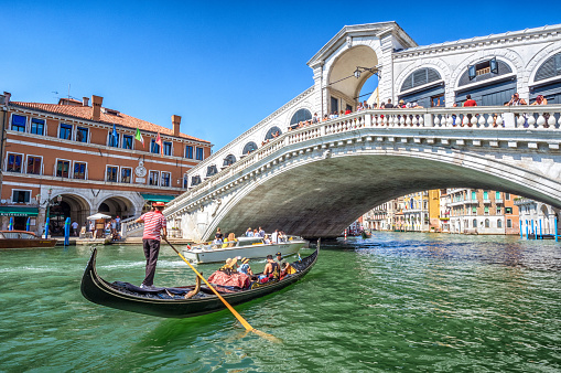 Venice, Italy – August 15, 2017:  Gondola with tourists on Gran Canal with Rialto Bridge, Venice