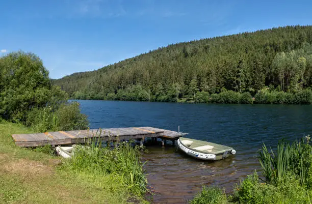 Wooden jetty with boat on a lake, taken at the dam Nagoldtalsperre in the Black Forest, Germany