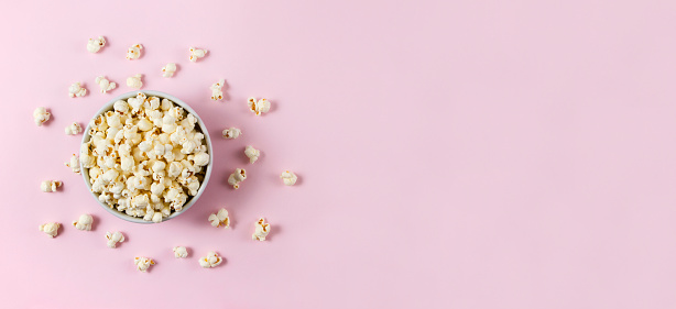 Stock photo of bucket of popcorn in cinema / movie theatre, movie snack. Caramelised / caramel toffee popcorn as movie snack food in paper cups with empty red seats in foreground.