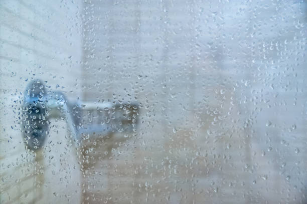 istock Fresh shower behind wet glass window with water drops splashing 1262966508