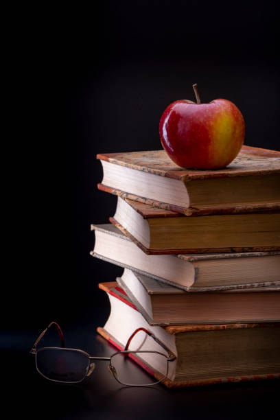 Five old books with an apple and glasses