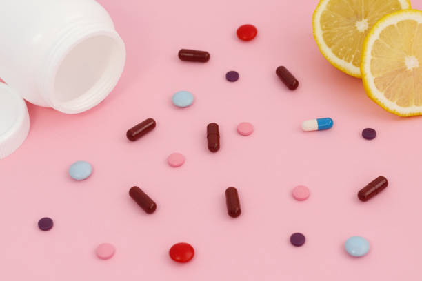 istock Assorted pharmaceutical medicine pills, tablets and capsules, lemon and bottle on pink background. 1262969799