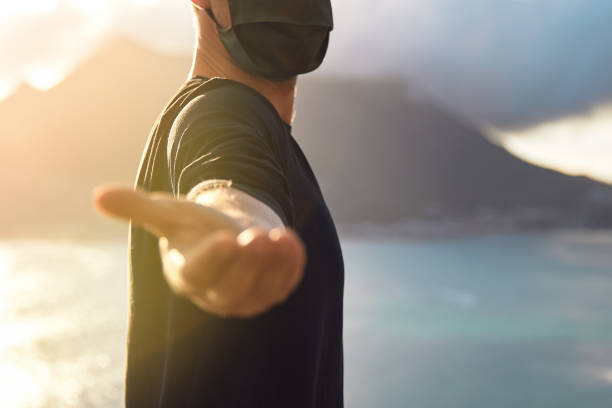 istock Man wearing face mask holding out his hand with scenic view. 1262971675