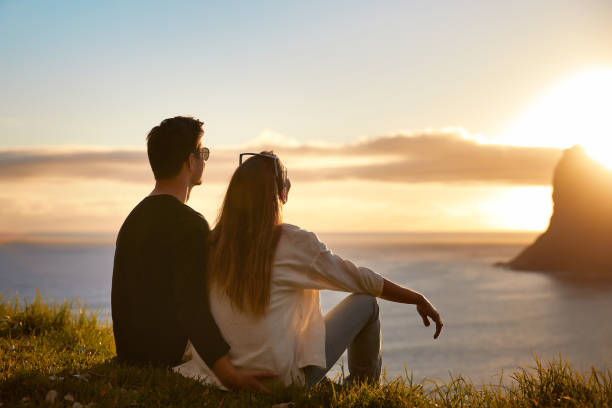istock Happy couple hugging looking at sunset with amazing mountain view. Warm evening sun light 1262971830