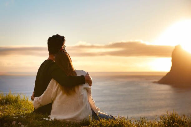 istock Happy couple hugging looking at sunset with amazing mountain view. Warm evening sun light 1262971900