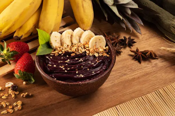 Acai berry bowl with fruits and cereals on wooden table