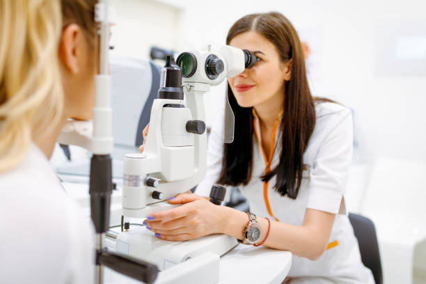 istock Female ophtalmologist looking through eye test equipment on eye exam 1262979607