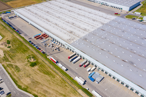 Aerial view of goods warehouse. Logistics center in industrial city zone from above. Aerial view of trucks loading at logistic center stock photo