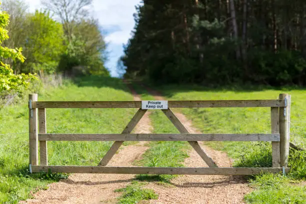 Photo of Private farm land fenced off by a large gate with a private keep out sign showing no access to the rural pathway