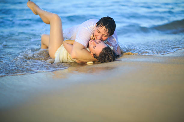 istock newlywed in wet clothes flirting lying on beach. 1262992064