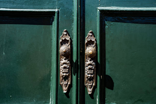istock Patterned metal door handles on green double-leaf doors. 1262993338