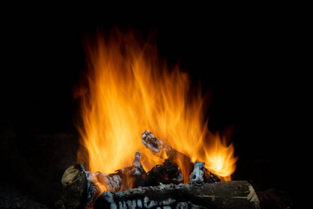 istock Flames in different forms of a bonfire made with orange tree trunks in long exposure with a black background 1262995050