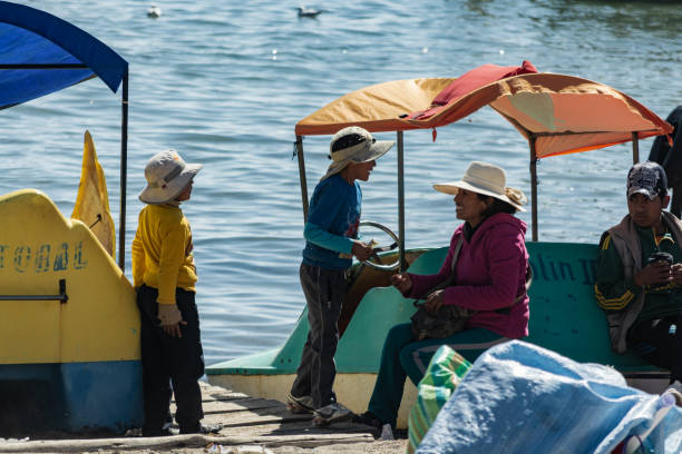 eine bolivianische familie in einem holzsteg bei sonnenuntergang in copacabana, bolivien - bolivia copacabana bolivian ethnicity lake titicaca stock-fotos und bilder