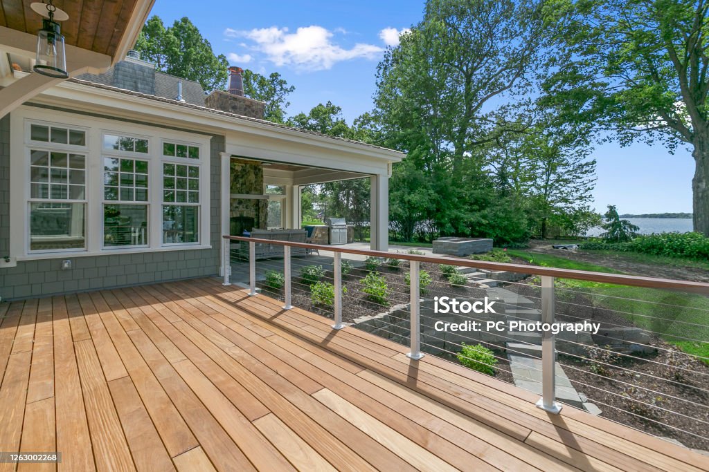 Wood deck of fabulous home on the shore's of a lake Lakeside luxury home with large wood deck and beautifully landscaped yard Deck Stock Photo