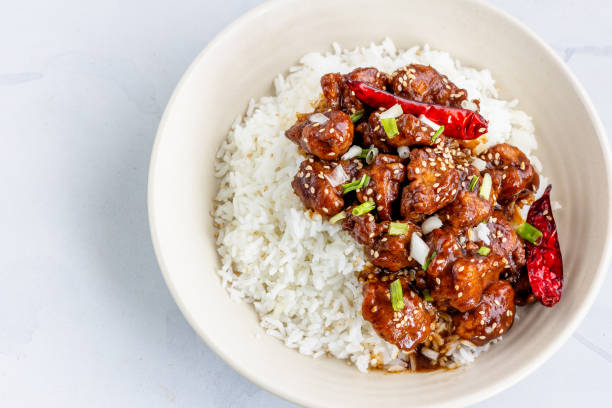 general tso's chicken on top of rice in a bowl garnished with sesame seeds and scallion top view food photography - chicken general tso food imagens e fotografias de stock