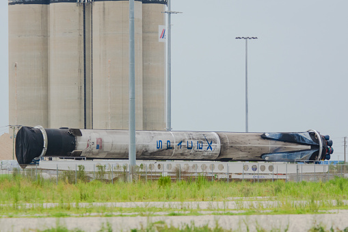 July 25, 2020 - Cape Canaveral, USA: A SpaceX Falcon 9 booster rocket is being moved over road by the rocket transporter. It was used on 2 launches and will be refurbished and used again. The view is from a public parking lot near the north cruise ship terminals of the port outside the Federal area of Cape Canaveral.