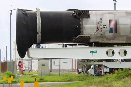 July 25, 2020 - Cape Canaveral, USA: A SpaceX Falcon 9 booster rocket is being moved over road by the rocket transporter. It was used on 2 launches and will be refurbished and used again. The view is from a public unrestricted road south of the Cape Canaveral AFS near the cruise terminals.