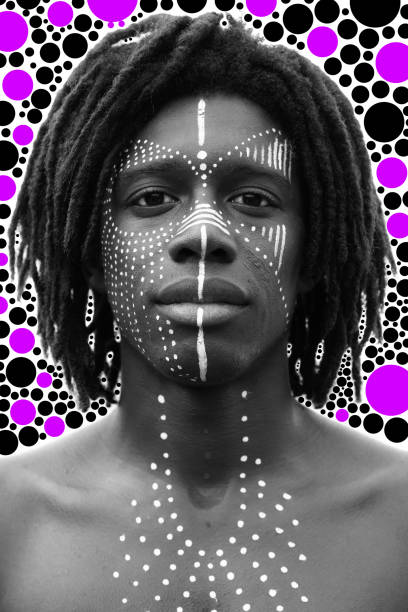 黒と白の深刻な表情でカメラをまっすぐに見てドレッドヘアと伝統的な顔の塗料を持つ若いアフリカ人男性の肖像画 - hairstyle fashion model make up fashion ストックフォトと画像