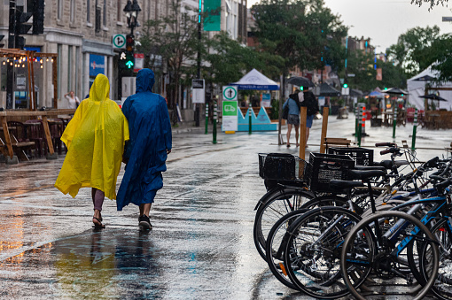 Montreal, CA - 30 July 2020: People on Mont-Royal Avenue wearing ponchos during rain & storm