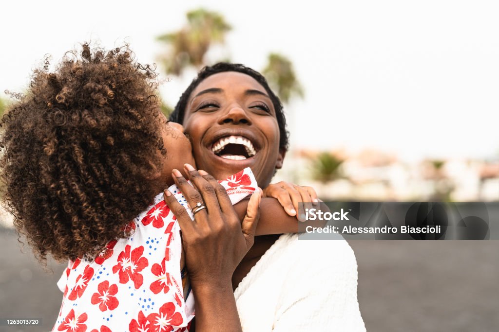 Happy African family on the beach during summer holidays - Afro American people having fun on vacation time - Parents love unity and travel lifestyle concept Family Stock Photo