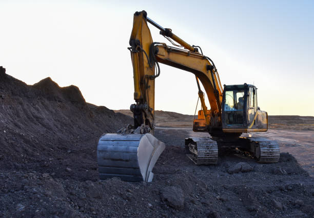 istock Excavator work at mining quarry on sunset background. Backhoe digs gravel. 1263014535