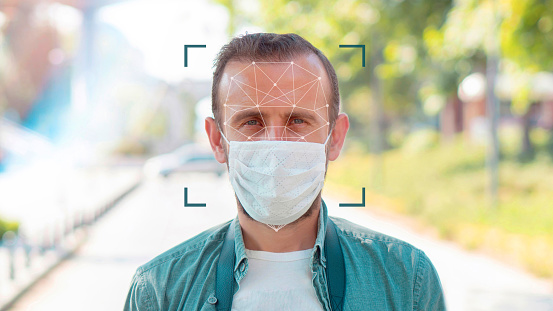 Portrait of young man putting on a protective mask, Facial Recognition System concept.