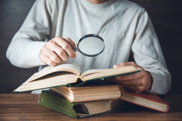 istock man hand magnifier and books on table 1263015920