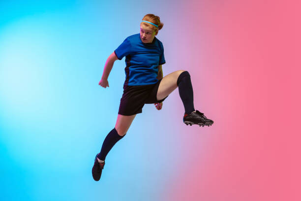 istock Female soccer, football player training in action isolated on gradient studio background in neon light 1263016328