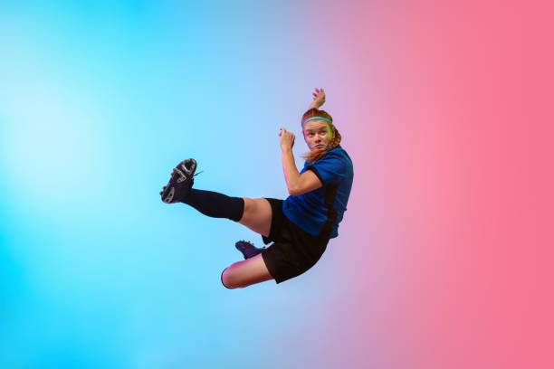 Female soccer, football player training in action isolated on gradient studio background in neon light