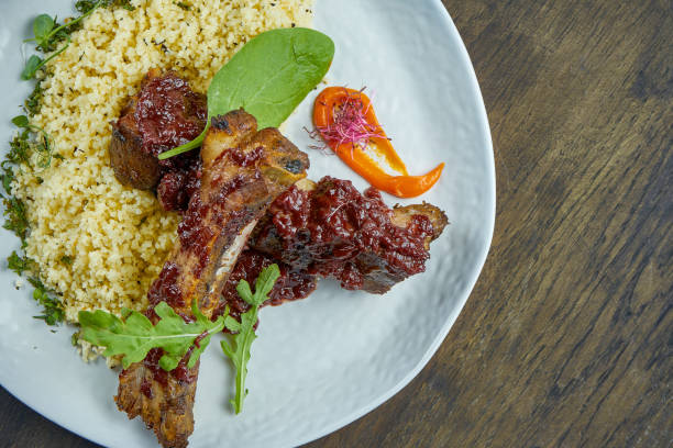 istock Appetizing grilled pork ribs with bulgur in a white plate on a wooden background. Selective focus. Roasted ribs 1263018631