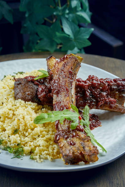 istock Appetizing grilled pork ribs with bulgur in a white plate on a wooden background. Selective focus. Roasted ribs 1263018636
