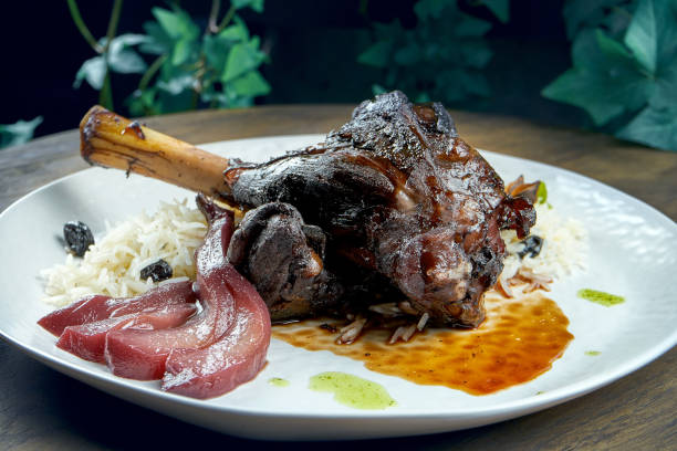 木製の背景に白い皿に米と梨を焼いたラムシャンク。 - lamb shank roast lamb leg of lamb ストックフォトと画像