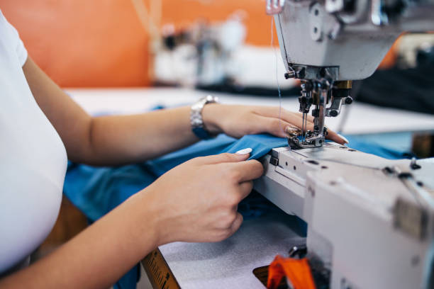 Textile Industry Workers Close up shot of professional seamstress hands working in tailoring or sewing industry production hall. seamed stock pictures, royalty-free photos & images