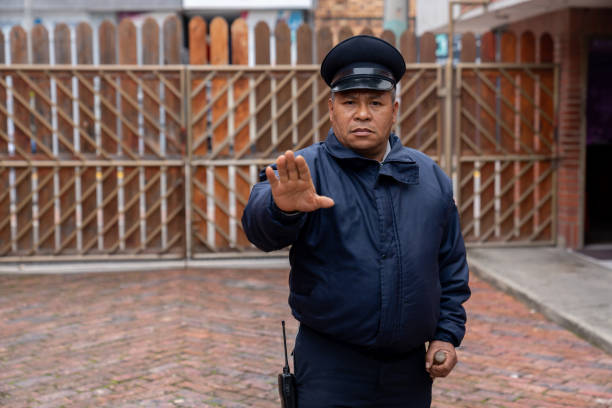 Portrait of Latin American security guard working at a gated community preventing people from getting in and making a stop! Gesture - safety concepts