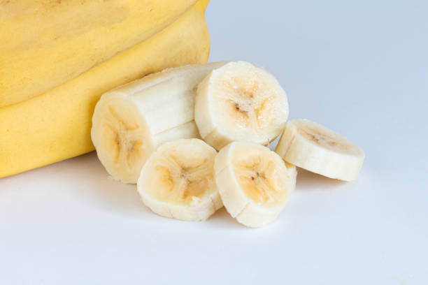 Ripe banana and slices of bananas with wooden fork in a piece of banana isolated on white background