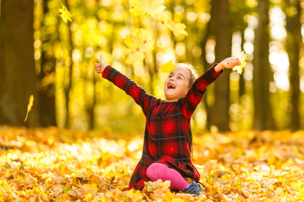 istock Very cheerful child having fun while tossing up yellow leaves 1263021800