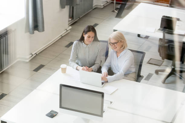 dojrzała bizneswoman mentor nauczania stażysta w biurze widok z góry - women togetherness teaching laptop zdjęcia i obrazy z banku zdjęć