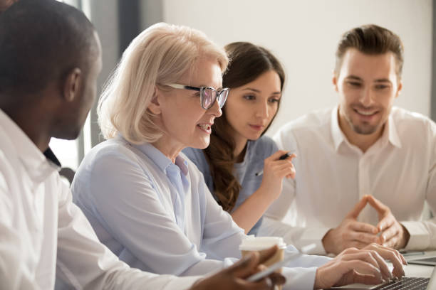 istock Mature businesswoman coach teaching diverse employees, using laptop 1263022898