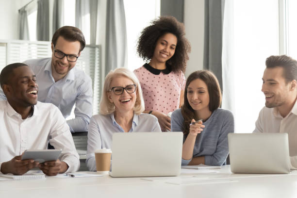 istock Smiling mature mentor teaching diverse employees team, using laptop 1263022901