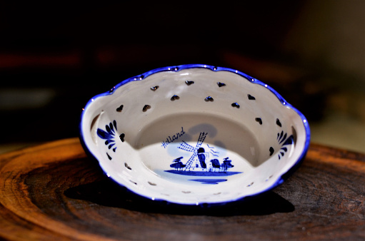 A white thin porcelain Dutch platter with blue motifs and hearts on the wooden board