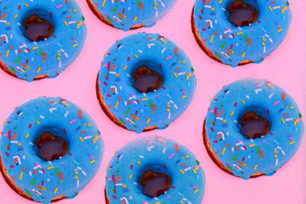 istock Harmful delicious blue doughnuts with pastry topping flat pattern on pink background. The view from the top. 1263027259