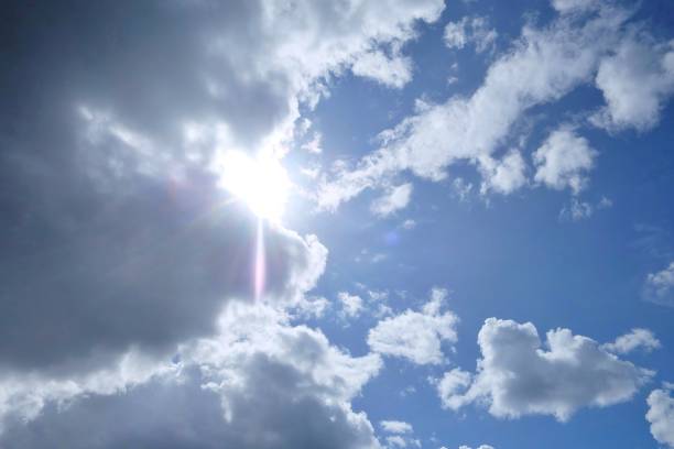 istock White fluffy clouds with blue sky and flare light 1263035672