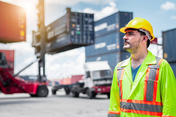 istock Confident Caucasian man engineer wearing yellow safety helmet using walkies talkie call to driver and check for control loading containers box from Cargo freight ship for import and export, transport 1263038024